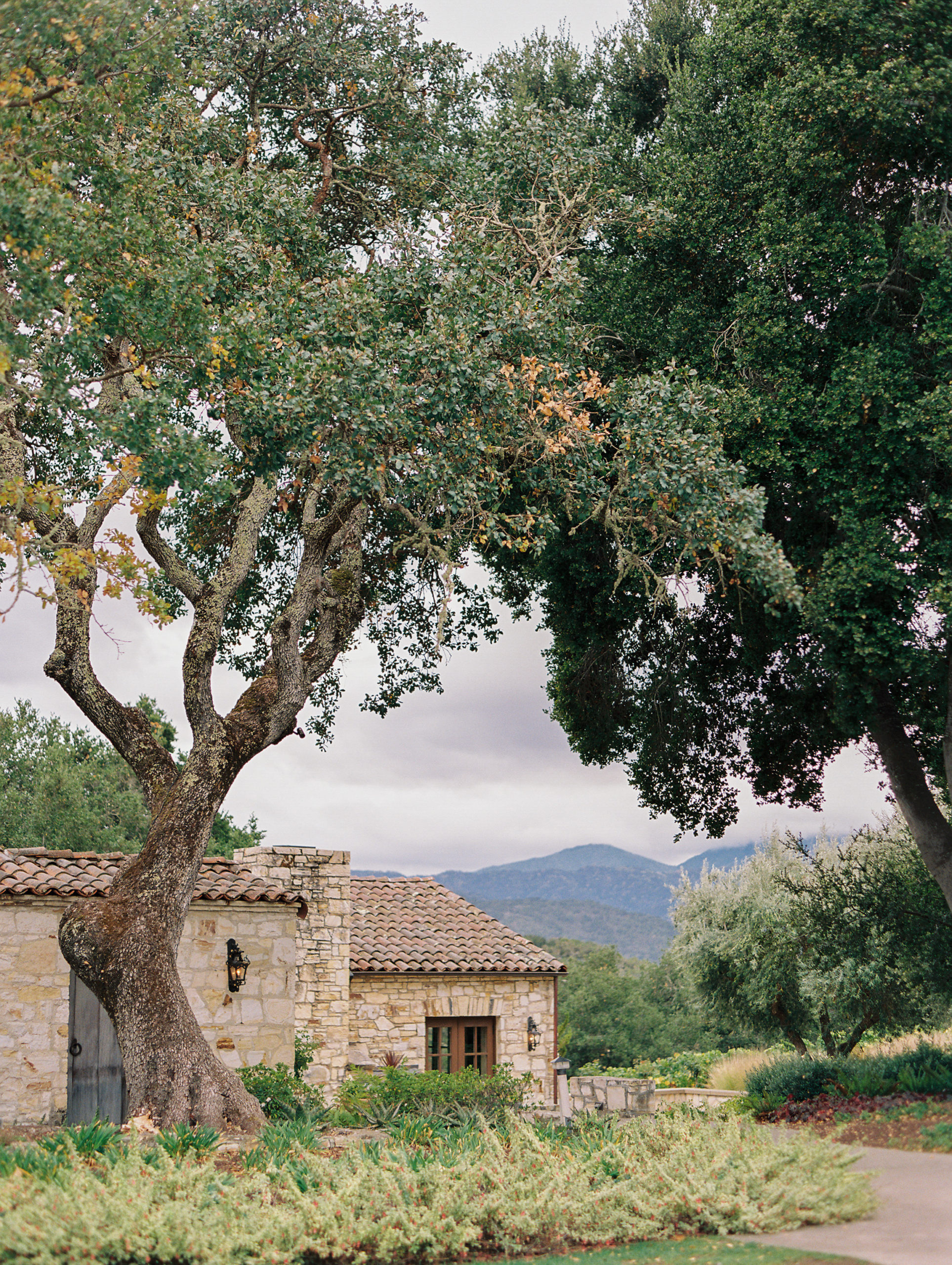 exterior photo of the stone facade of the holman ranch villa surrounded by trees.